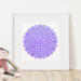 Leaning against a wall, beside a stuffed animal, and framed in a white square frame, is the purple, round amulet.